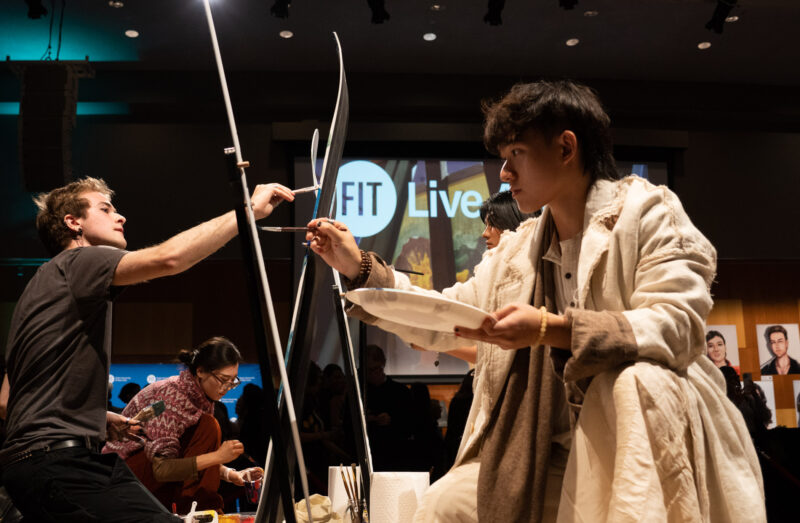 Four students painting on snowboards in a dark room