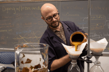 Julian Silverman in his classroom pouring a yellow substance into a beaker