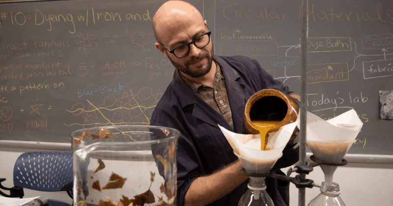 Julian Silverman in his classroom pouring a yellow substance into a beaker