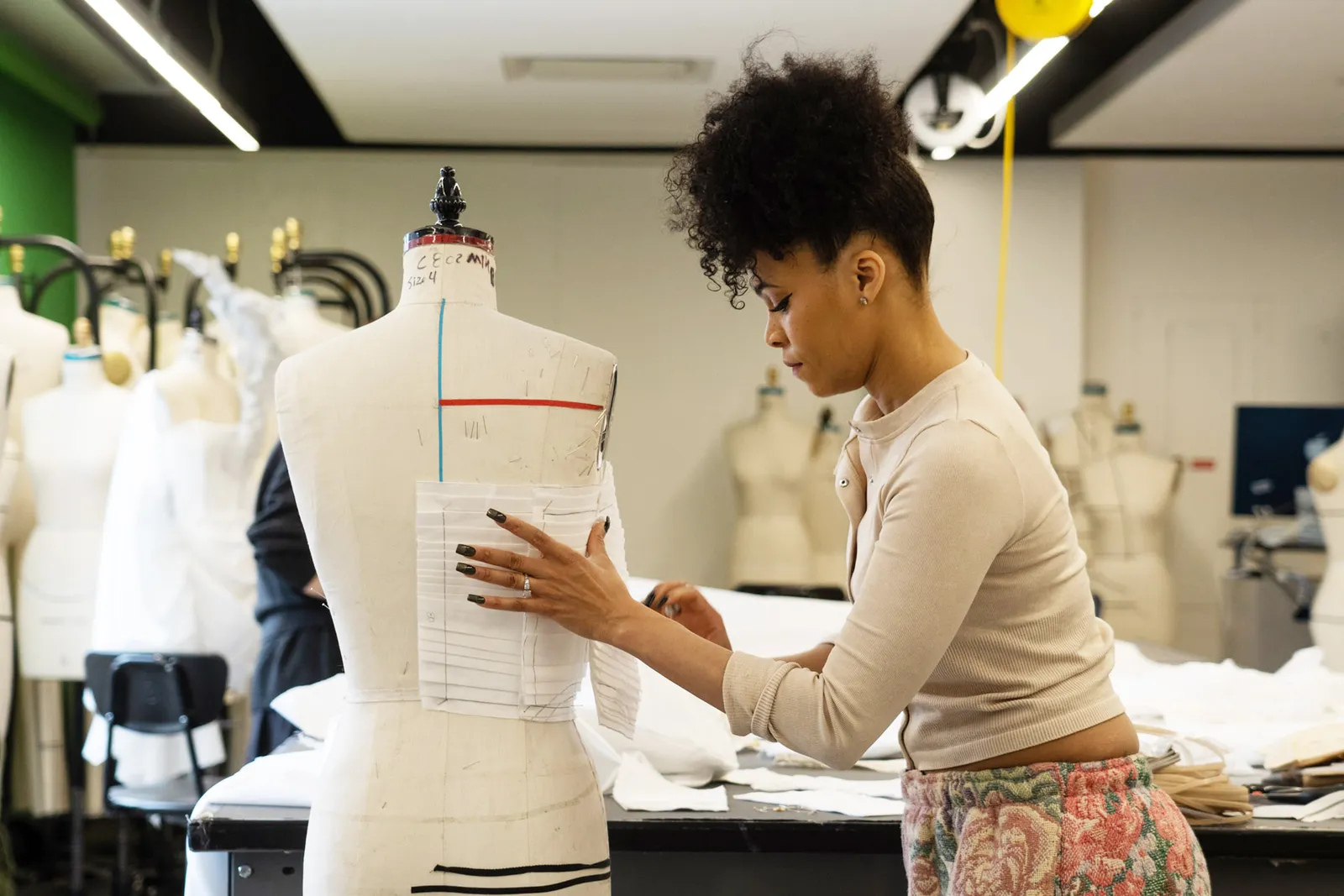 student working on a garment at a dress form in an FIT classroom