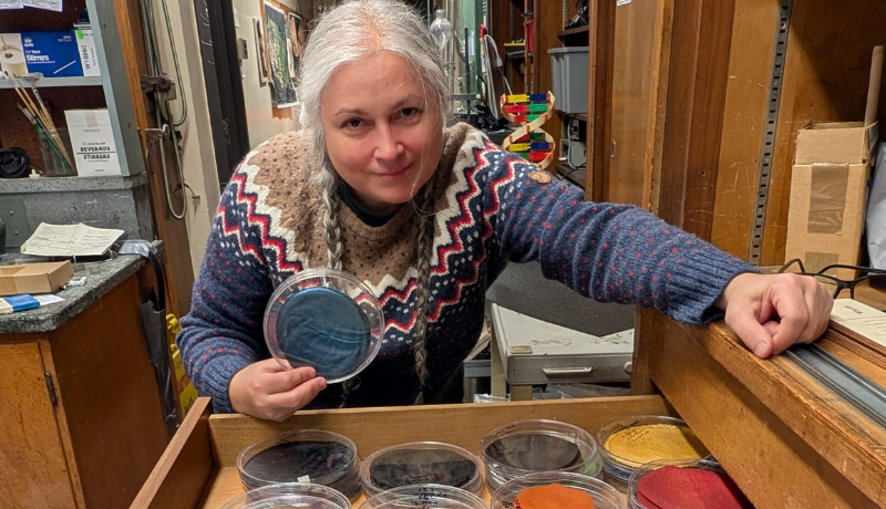 Gwen Sanchirico leans over a drawer of colorful glass petri dishes 
