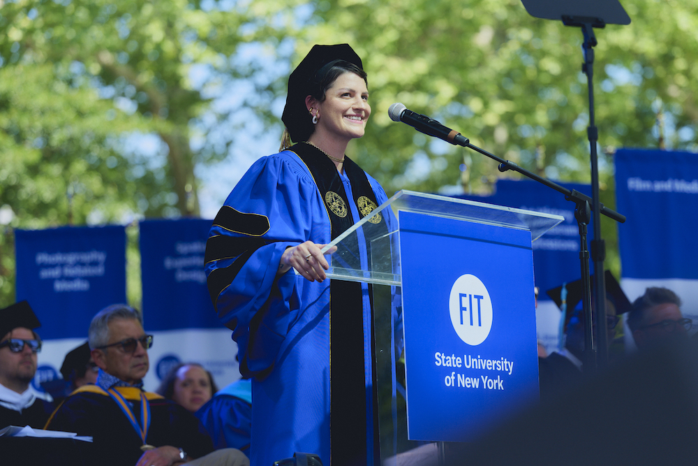 Jeriana San Juan in regalia at the FIT commencement lecturn.