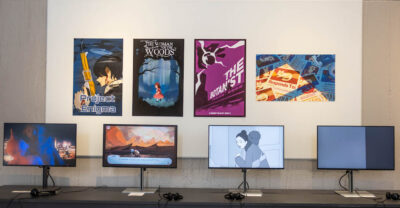 posters designed by students on the wall and monitors also displaying student work