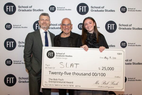 President Jason Schupbach, Bob Fisch, and Delaney Slattery stand in front of a step and repeat banner; Slattery is holding a oversized check to her business SLAT