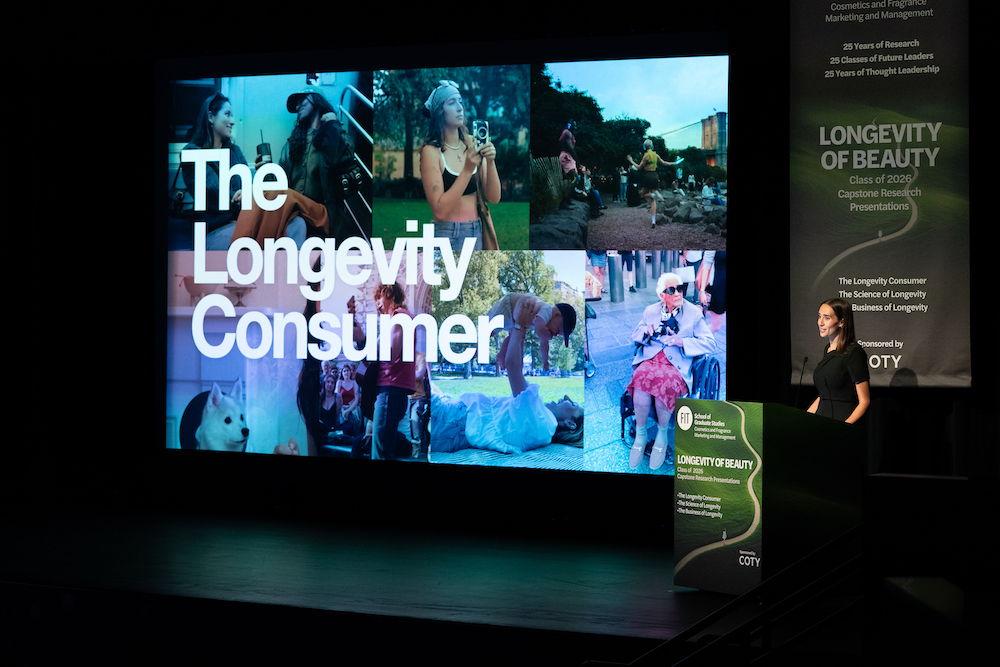 student at a lectern giving a presentation with a large screen to her right with a montage of images of people doing daily things with the text 'The Longevity Consumer'