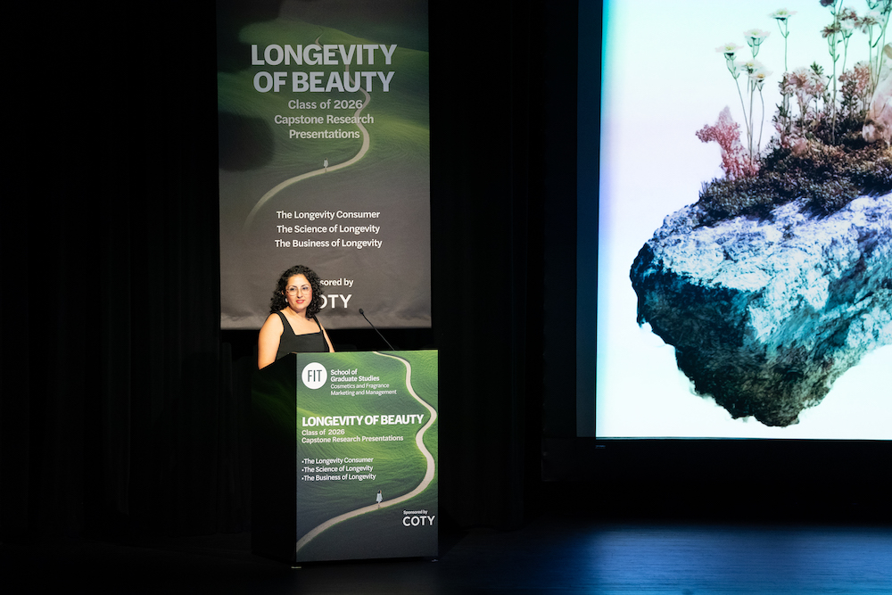 student presenter stands at a lectern with a screen to her left showing a rock with plants growing on it