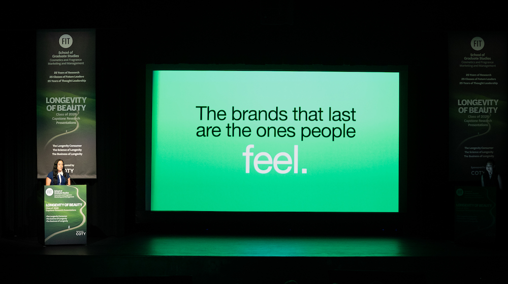 student presenter stands at a lectern with a screen to her left showing text: The brands that last are ones people feel.
