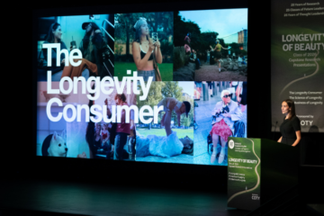 student at a lectern giving a presentation with a large screen to her right with a montage of images of people doing daily things with the text 'The Longevity Consumer'