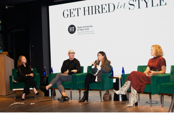 four panelists sitting on chairs on stage with screen behind them