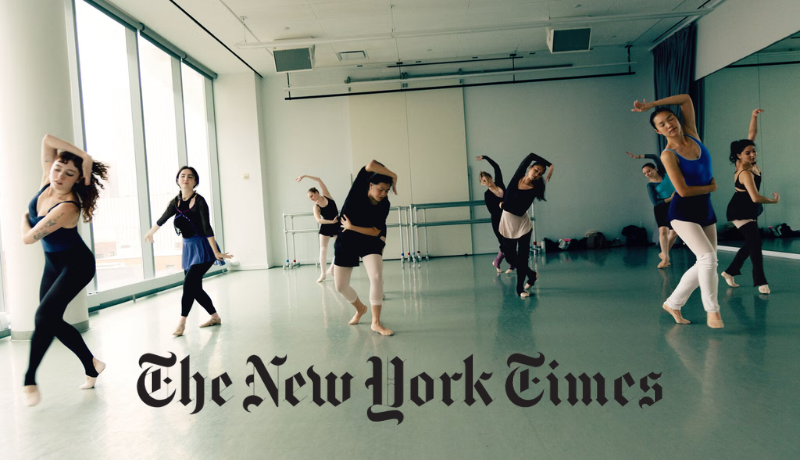 Several ballet dancers mid movement with arms over their heads in a studio